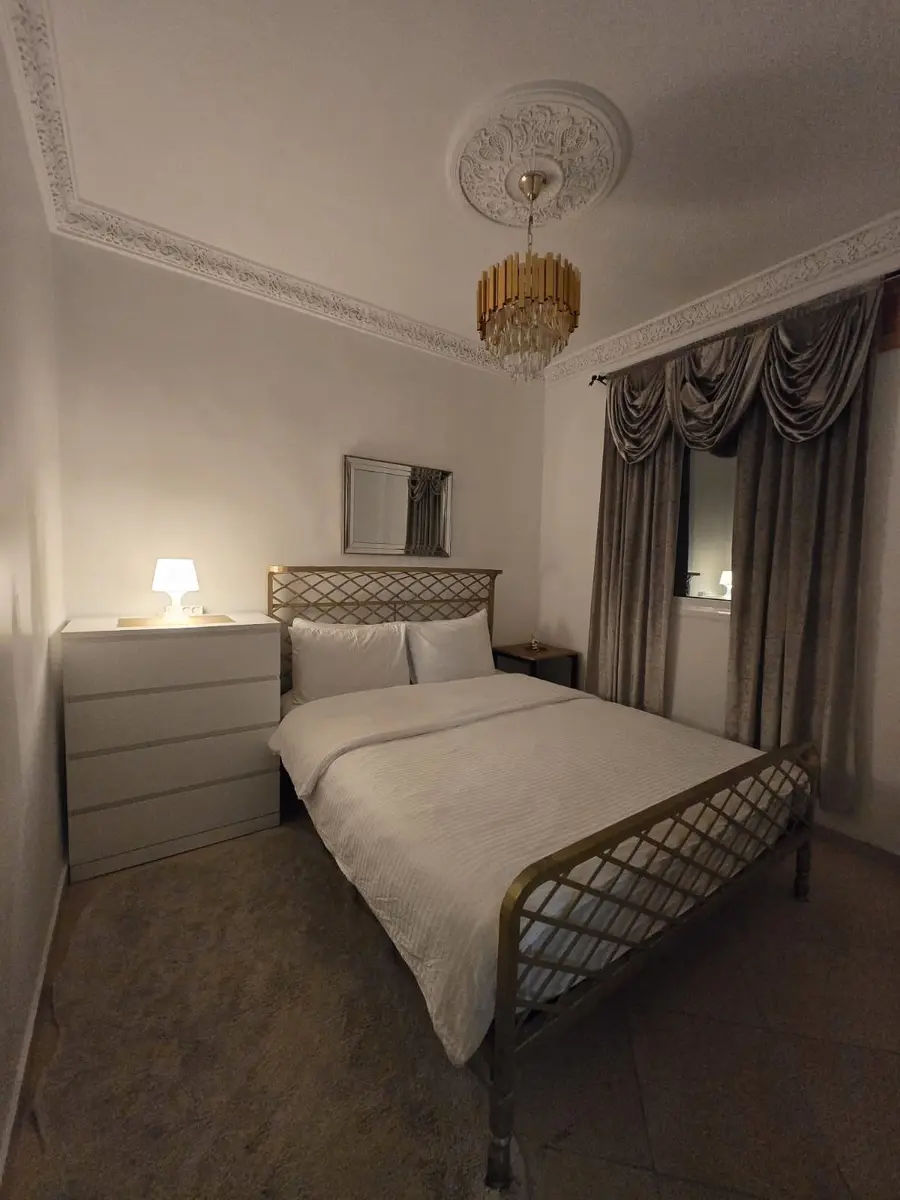 Bedroom with queen bed, dresser, and curtained window