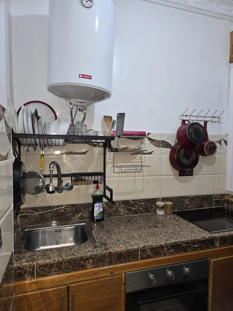 Kitchen cooking area with oven, induction hob, and utensils