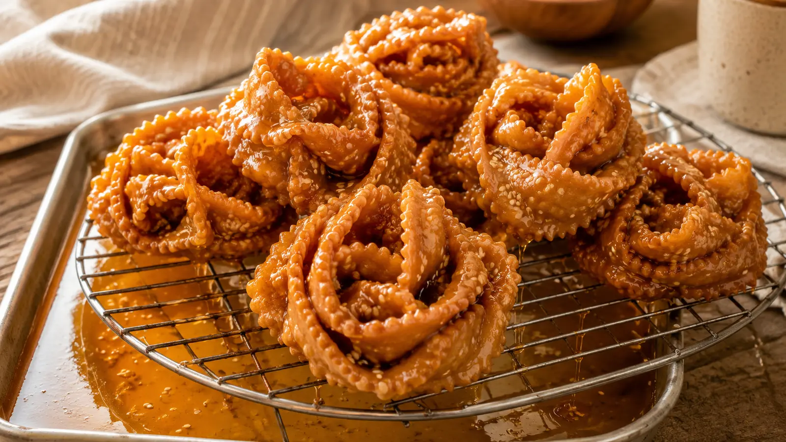 Golden flower-shaped Moroccan chebakia pastries draining above orange blossom honey