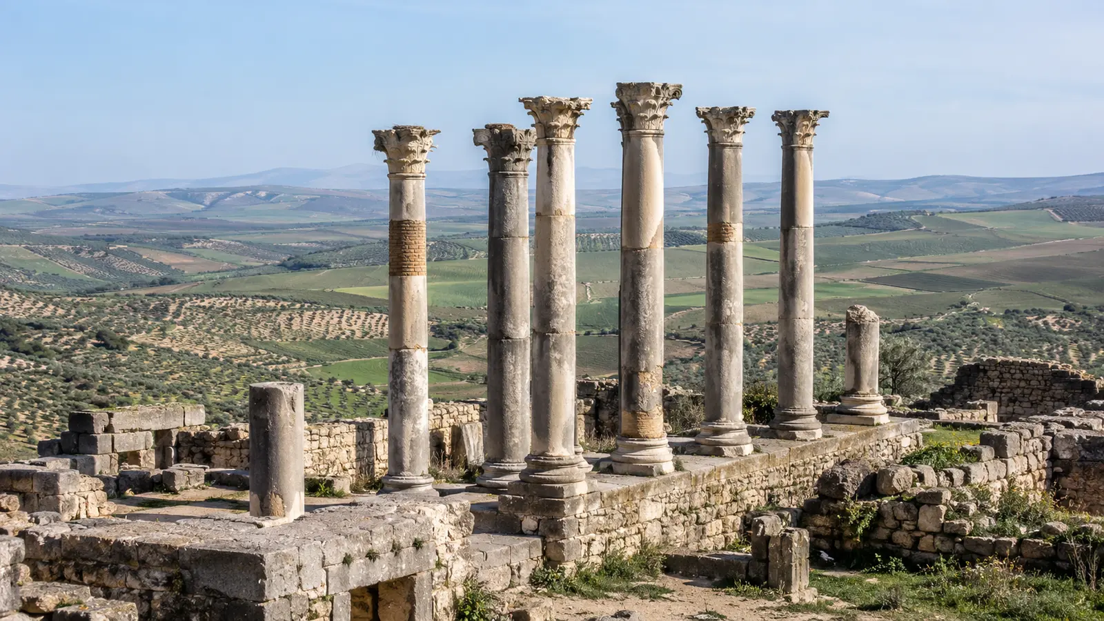 Roman columns at Volubilis overlooking green Moroccan farmland