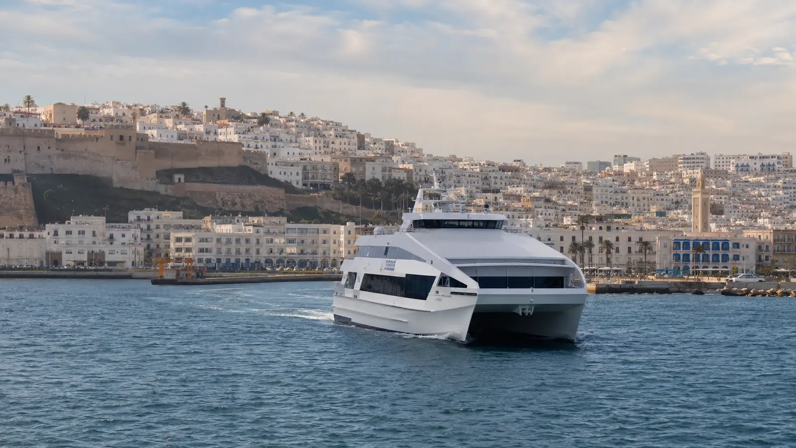 Passenger ferry approaching Tangier Ville beneath the Tangier kasbah skyline